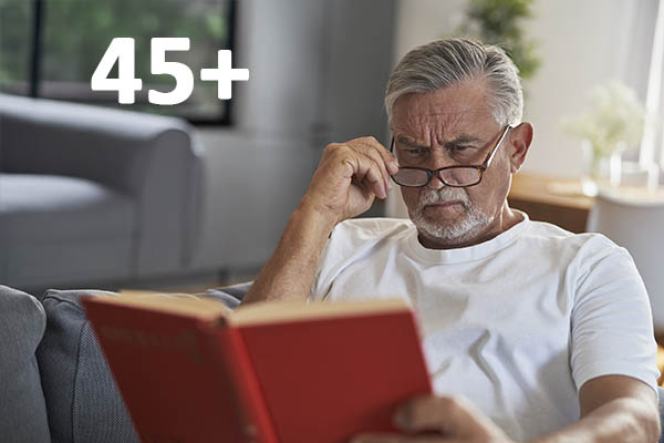 Senior caucasian man reading book and lying at the couch